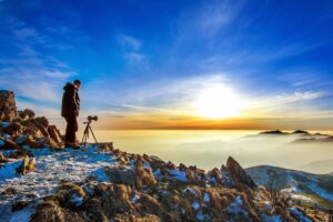 Person on rocks with camera at sunset